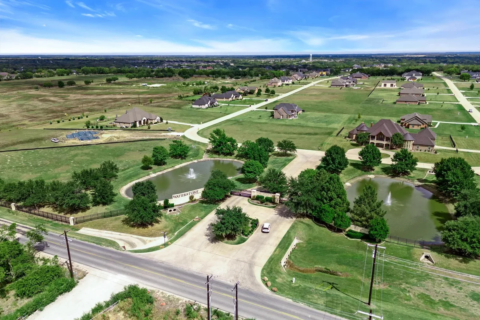 Wider aerial of Waterstone Estates entry, pond, and nearby residences